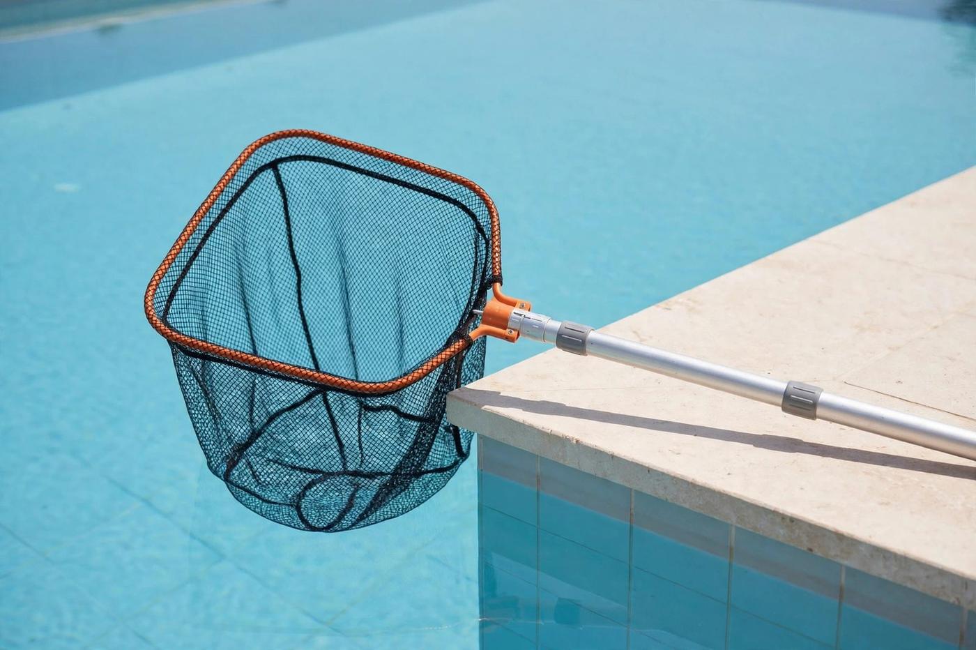 Pool skimmer net at the edge of a clear pool